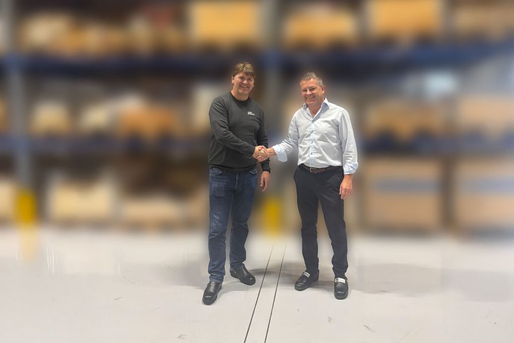 Two men are facing camera and shaking hands.